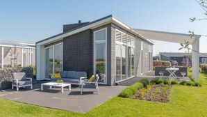 Une maison moderne dotée d’un patio aménagé avec un canapé, des fauteuils et une table.