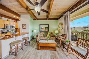 A spacious living area with a wooden ceiling, a kitchen with modern appliances, and a balcony with outdoor seating. - Renovated home across the street from the beach with shared pool & hot tub (Kailua-Kona)