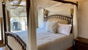 A four-poster canopy bed with white linens and a woven headboard.