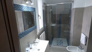 Un bagno con doccia, lavandino e specchio.