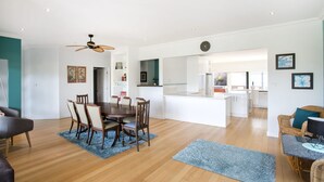 Une cuisine moderne avec des meubles blancs, un îlot central et un coin repas comprenant une table ronde et des chaises.