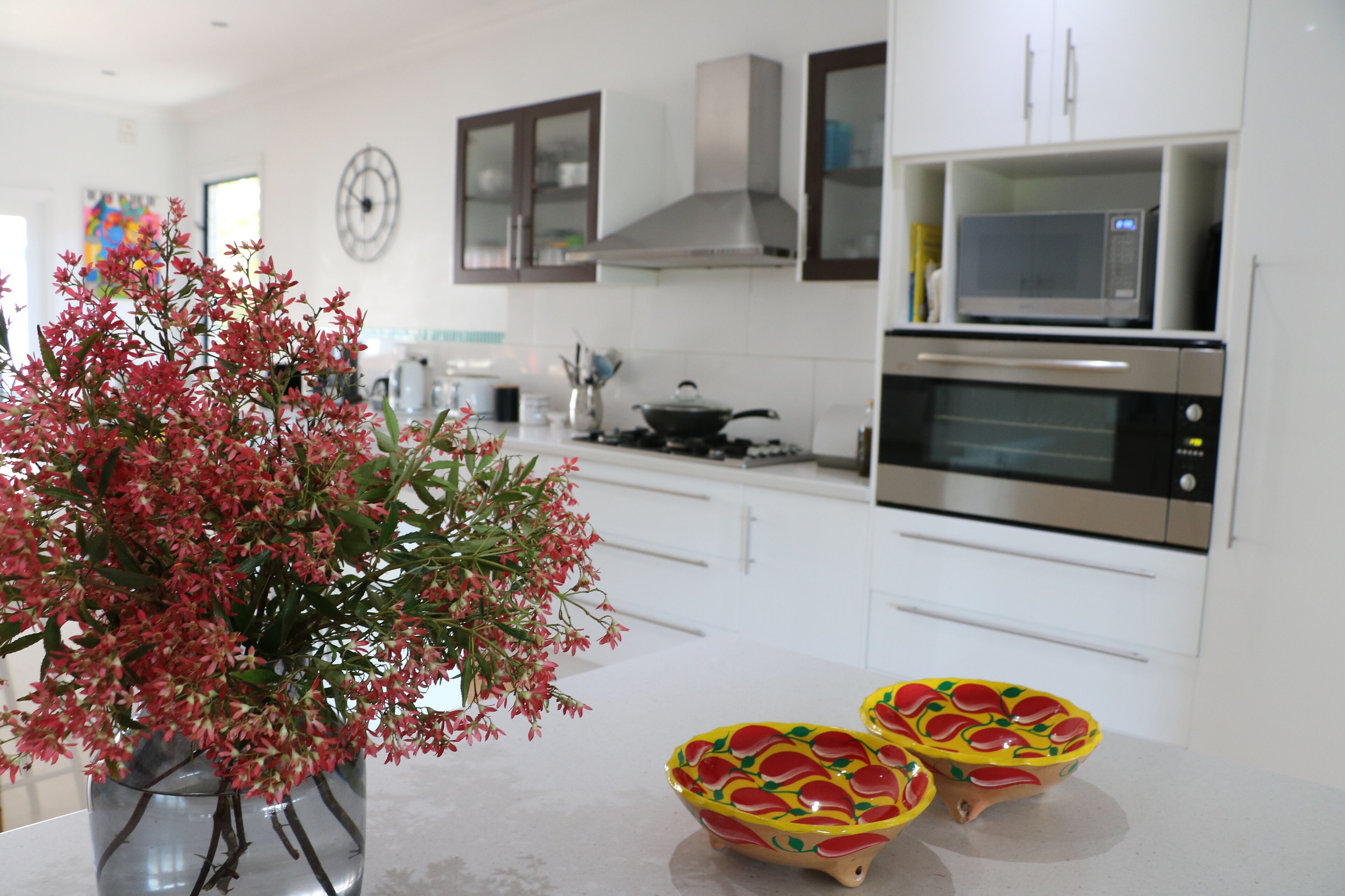 Una cucina moderna con mobili bianchi, elettrodomestici in acciaio inossidabile e una pianta decorativa.