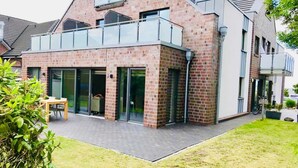 A modern house with a brick facade, large glass doors, and a balcony. - Papen, A. Ferienwohnung An Bord - An Bord (Varel)