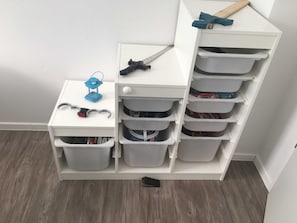 A white storage unit with multiple compartments, a small table with a blue toy and a measuring tape, and a hammer on top.