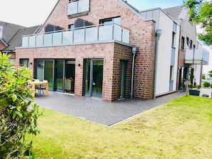 A modern house with a brick facade, large glass doors, and a balcony.