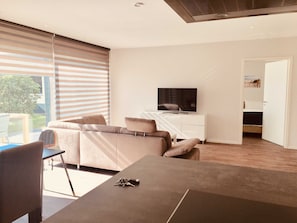 A modern living room with a sofa, TV, and dining area.