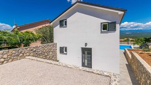 A two-story house with a stone wall and a swimming pool in the background. - Holiday house SAN MICHELE (Vrh)