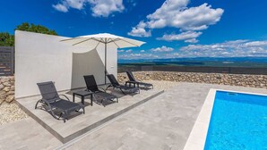A poolside area with lounge chairs and an umbrella, overlooking a scenic landscape. - Holiday house SAN MICHELE (Vrh)