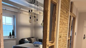 Un salon moderne avec un coin repas, des poutres en bois et une vue sur l’extérieur.