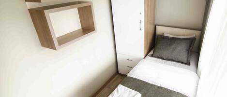 A bedroom with a bed, a wardrobe, and built-in shelves.