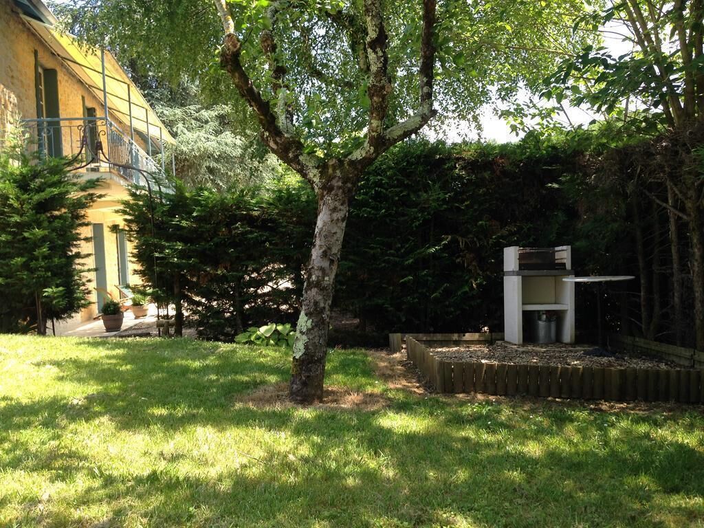 A courtyard with a tree, a small white structure, and a building with a yellow facade.