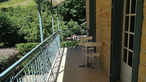 Ein überdachter Balkon mit Metallgeländer, einem kleinen Tisch und einem Stuhl.