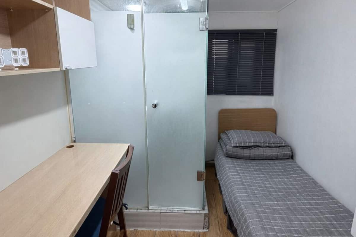 A compact room with a bed, a desk, and a wardrobe.