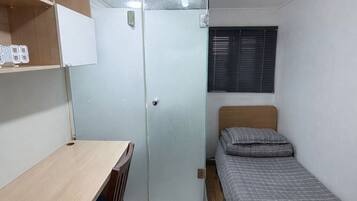 A compact room with a bed, a desk, and a wardrobe.