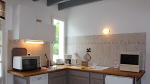 Eine kleine Küche mit Mikrowelle, Kaffeemaschine und einem Kühlschrank.