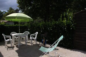 An outdoor seating area with a table and chairs, a green umbrella, and a wooden fence.