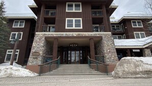 Un hotel de varios pisos con fachada de piedra, una entrada central con una escalera y balcones en cada planta.