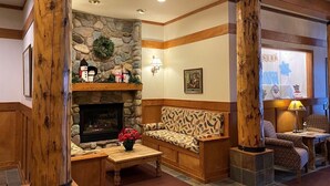 Un hall acogedor con chimenea de piedra, muebles de madera y pared de piedra.