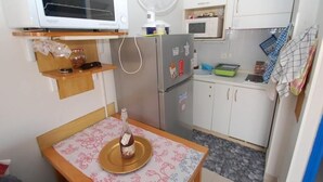 Une cuisine compacte équipée d’un four à micro-ondes, d’un réfrigérateur et d’un ventilateur.