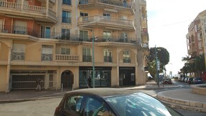 Un immeuble à plusieurs étages doté de balcons, d’un panneau indiquant un parking et d’un passage piéton.
