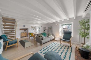Ein geräumiges Wohnzimmer mit hohen Decken, einem Essbereich und Blick ins Freie.