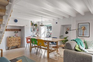 Un espacio moderno para vivir con una mesa de comedor de madera, sillas coloridas, un sofá gris y una escalera.