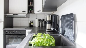 Una cocina moderna con horno empotrado, cafetera y lavabo con tabla de cortar.