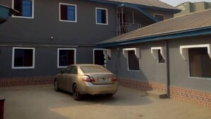 A multi-story building with a car parked in front. - Perfecto Hotel Suites Lounge (Ibadan)