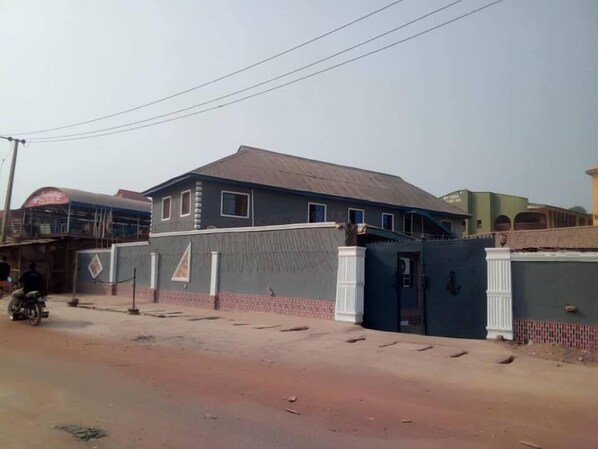 A residential building with a gated entrance, a tiled roof, and a brick base. - Perfecto Hotel Suites Lounge (Ibadan)
