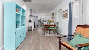 Una cocina moderna con armarios blancos, una mesa de comedor con sillas y una estantería azul.