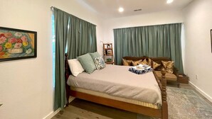 Un dormitorio con cama, mesita de noche, cómoda y un cuadro en la pared.