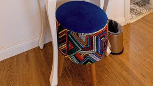 A white vanity with a mirror, a small drawer, and a blue stool with a colorful geometric pattern. - Fitoz Otel (Bozcaada)
