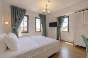 A bedroom with a bed, curtains, a TV, and a wardrobe.
