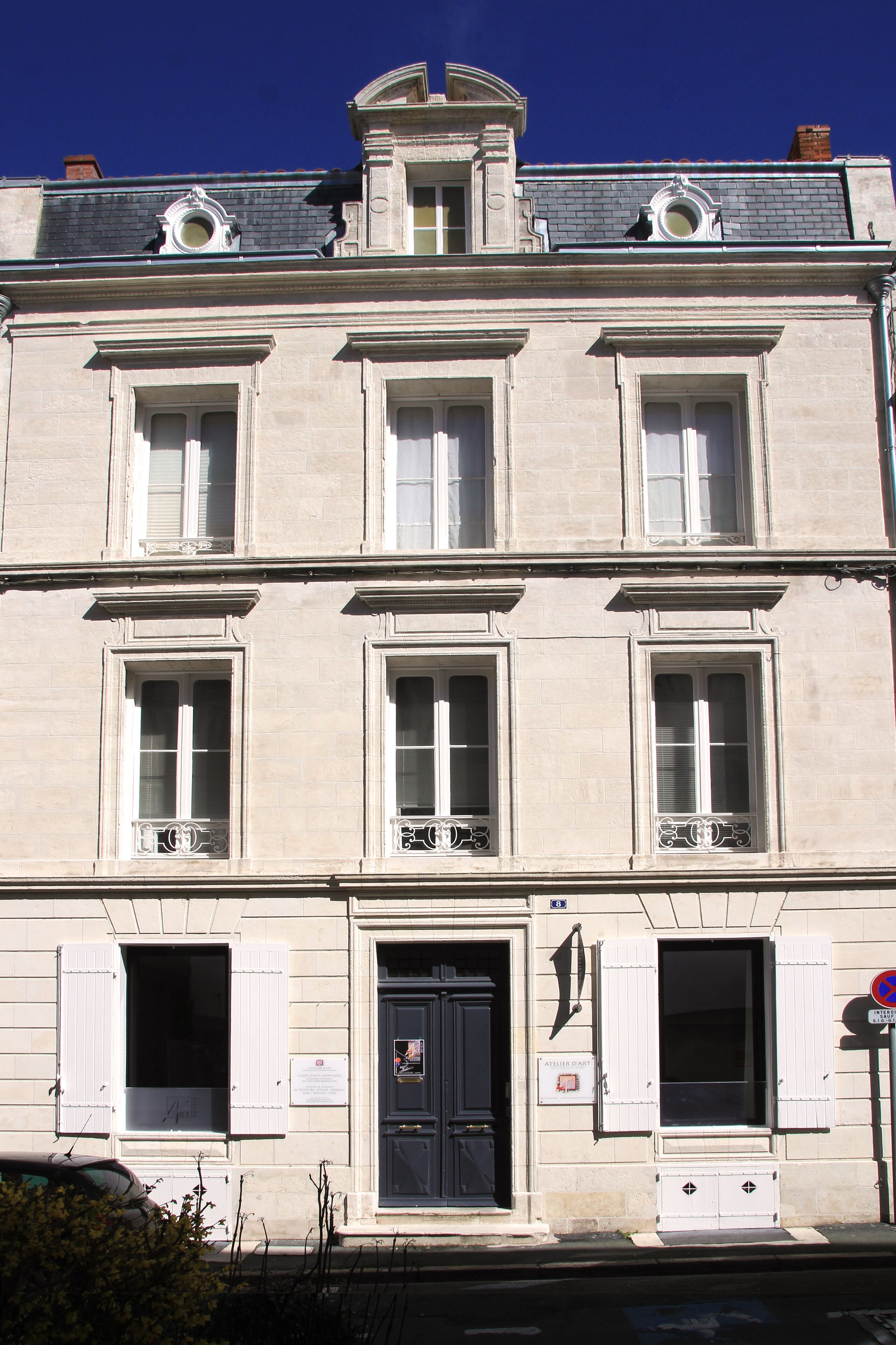 Un immeuble à plusieurs étages, de style architectural classique, caractérisé par des fenêtres disposées de manière symétrique et une entrée centrale.
