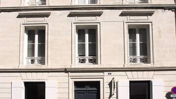 Un immeuble à plusieurs étages, de style architectural classique, caractérisé par des fenêtres disposées de manière symétrique et une entrée centrale.
