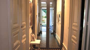 Un couloir avec un sol à carreaux, une petite table et des tableaux encadrés accrochés aux murs.