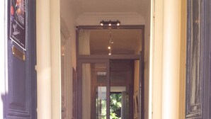 Un couloir doté d’un sol à carreaux, de colonnes blanches et de portes en bois foncé.