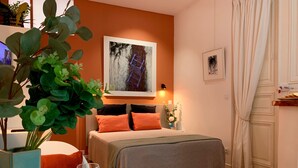 Une chambre confortable avec un lit, une table de chevet sur laquelle se trouve un verre d’eau et un panier de fruits.