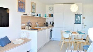 A modern kitchen with white cabinetry, a built-in oven, and a dining area with a white table and chairs. - Air-conditioned 1BR apartment with parking in Cavalaire-sur-Mer (Cavalaire-sur-Mer)
