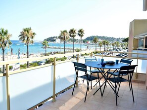 A balcony with a table and chairs overlooking a beach with palm trees and boats. - Air-conditioned 1BR apartment with parking in Cavalaire-sur-Mer (Cavalaire-sur-Mer)