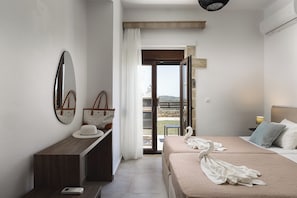 A hotel room with a bed, a desk, a mirror, and a view of the outside.
