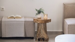 Una stanza con un divano, un tavolino in legno con una pianta e una candela, e una sedia.