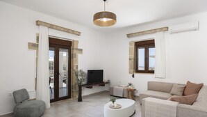 Un soggiorno moderno con un divano, un tavolino, una TV e una lampada a soffitto.