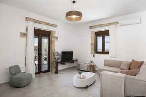 A living room with a TV, sofa, armchair, and a coffee table.