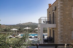 A stone building with a balcony, outdoor seating, and a pool.