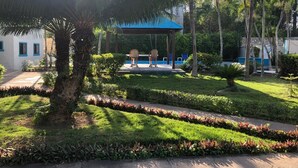 A well-maintained garden with a gazebo, palm trees, and a pool area.