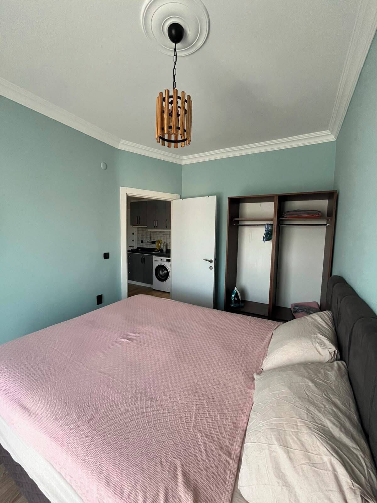 A bedroom with a bed, a wardrobe, a mirror, and a ceiling light fixture.