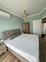 Un dormitorio con cama, armario, espejo y lámpara colgante.