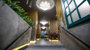 Un hall d'hôtel moderne, agrémenté d'un imposant lustre, d'un espace salon et d'un meuble à vin.