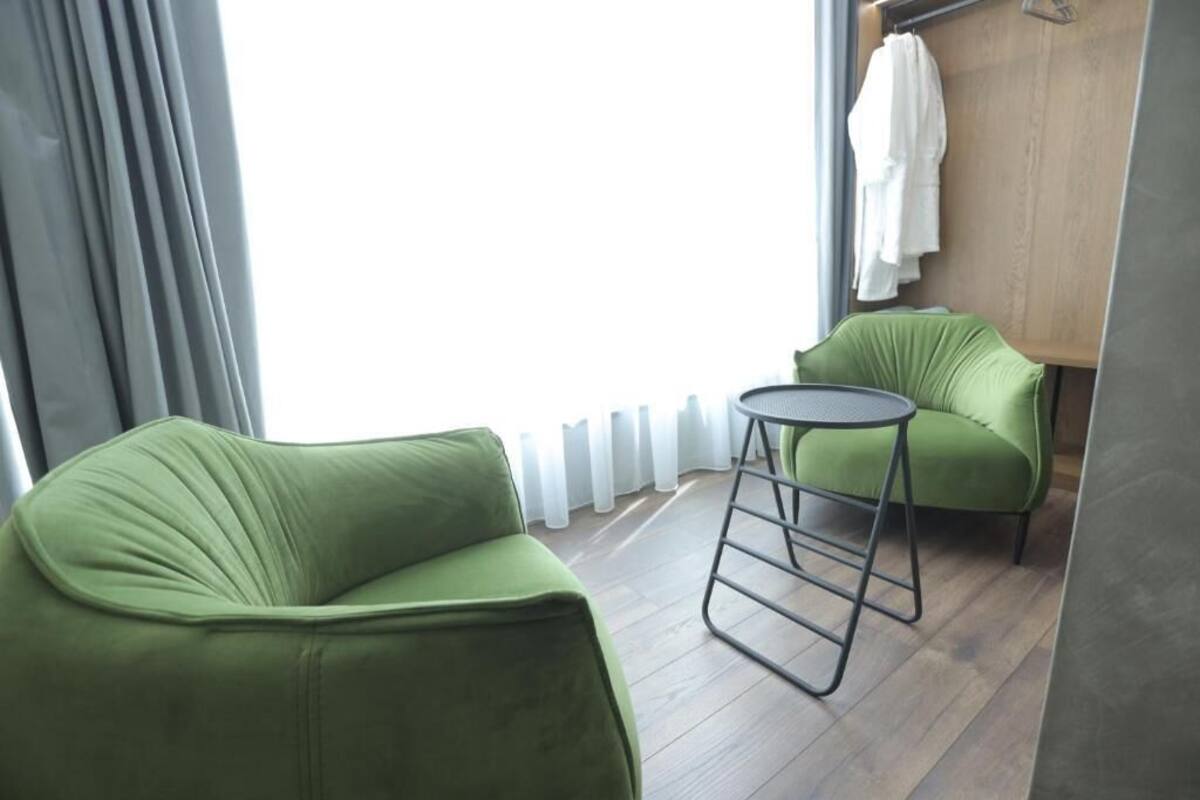 A room with a green sofa, a small round table, and a wooden wall with a towel hanging.
